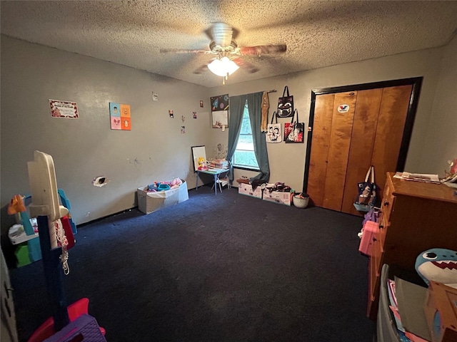 recreation room with carpet floors, ceiling fan, and a textured ceiling