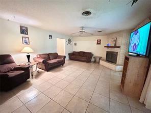 living area with a ceiling fan, a fireplace, and light tile patterned floors