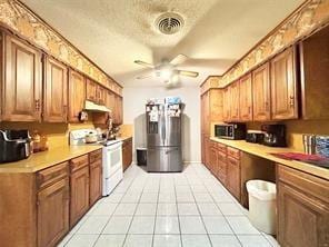 kitchen with light tile patterned floors, visible vents, brown cabinetry, stainless steel appliances, and light countertops