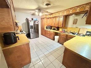 kitchen with appliances with stainless steel finishes, light tile patterned floors, a textured ceiling, and a ceiling fan