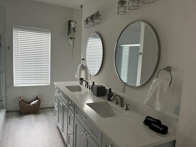 full bath featuring double vanity, a shower with door, a sink, and wood finished floors