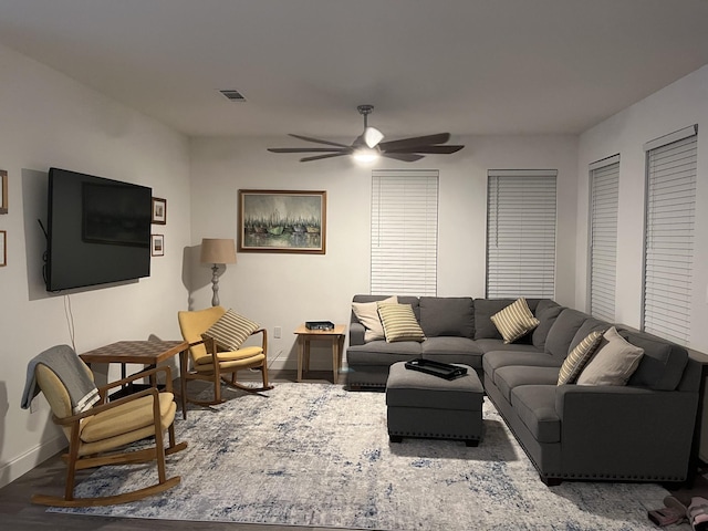 living room featuring baseboards, visible vents, a ceiling fan, and wood finished floors