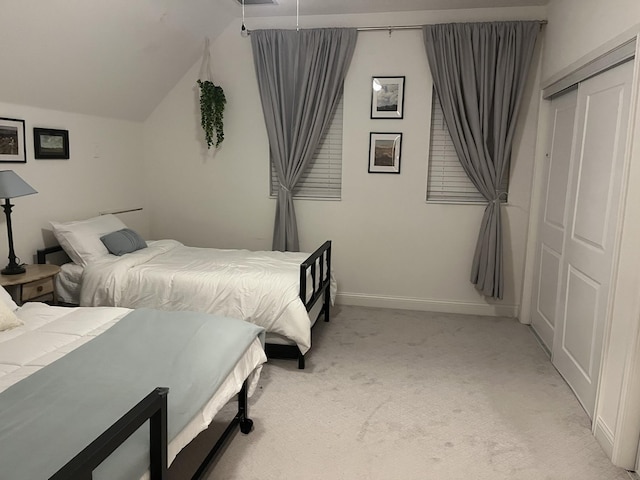 bedroom featuring light carpet, vaulted ceiling, a closet, and baseboards