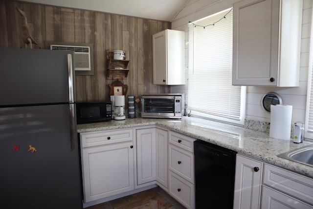 kitchen with light stone counters, a toaster, white cabinets, vaulted ceiling, and black appliances