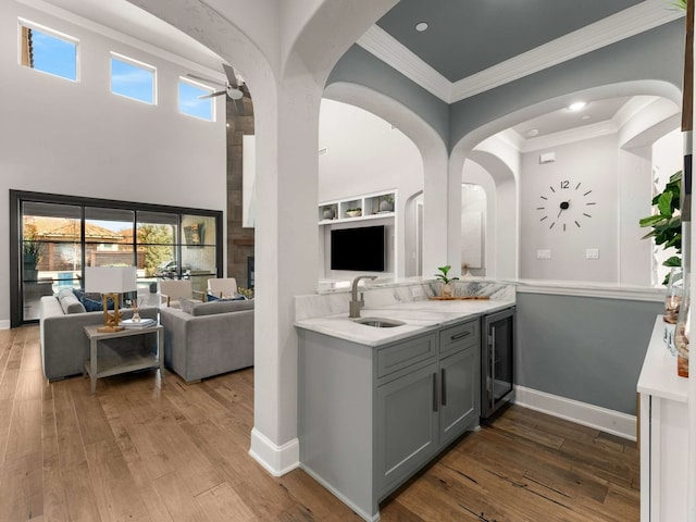 interior space featuring beverage cooler, open floor plan, wood finished floors, and a sink