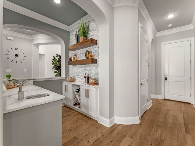 hall featuring a sink, recessed lighting, crown molding, and light wood finished floors