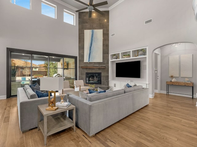 living area with wood finished floors, a ceiling fan, visible vents, arched walkways, and ornamental molding