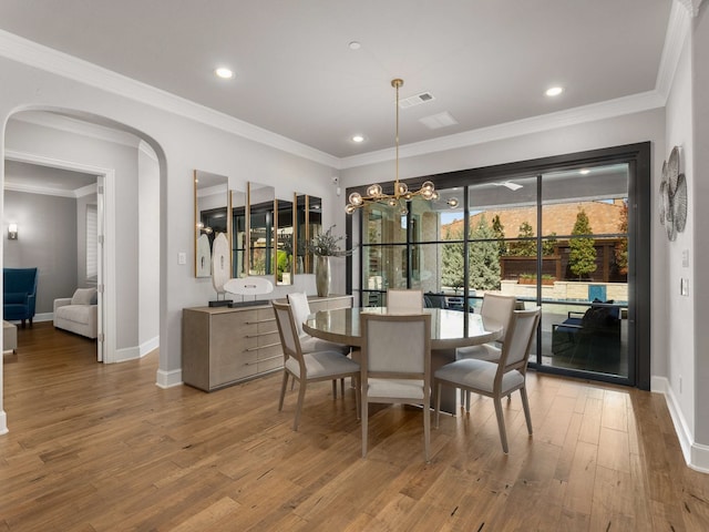 dining space featuring visible vents, arched walkways, wood finished floors, and crown molding