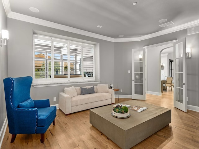 living area featuring light wood-style flooring, french doors, visible vents, and arched walkways