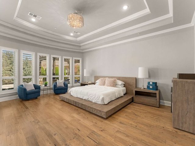 bedroom featuring hardwood / wood-style floors, a tray ceiling, visible vents, and ornamental molding