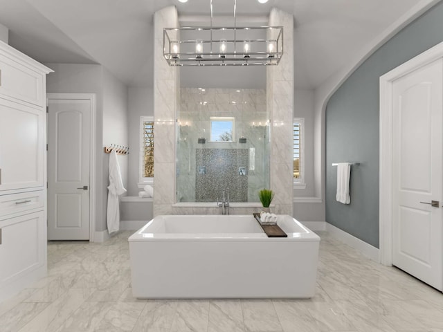 bathroom featuring baseboards, a soaking tub, lofted ceiling, a shower stall, and marble finish floor