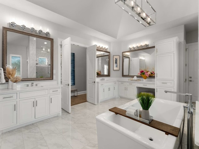 bathroom with a soaking tub, marble finish floor, vanity, and lofted ceiling