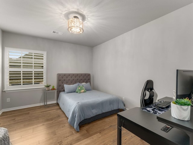 bedroom featuring visible vents, baseboards, and wood finished floors