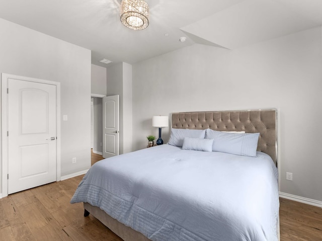 bedroom featuring a notable chandelier, wood finished floors, and baseboards