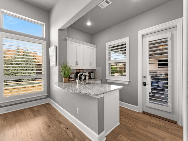 kitchen featuring visible vents, baseboards, hardwood / wood-style floors, and white cabinetry