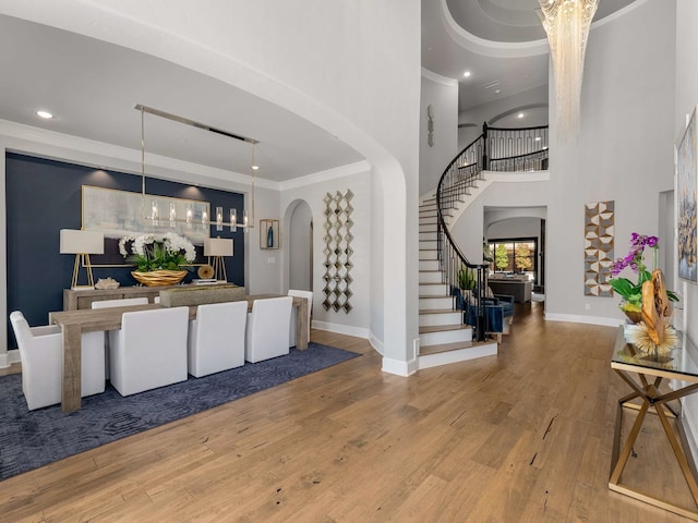 foyer entrance with arched walkways, stairway, ornamental molding, and hardwood / wood-style flooring