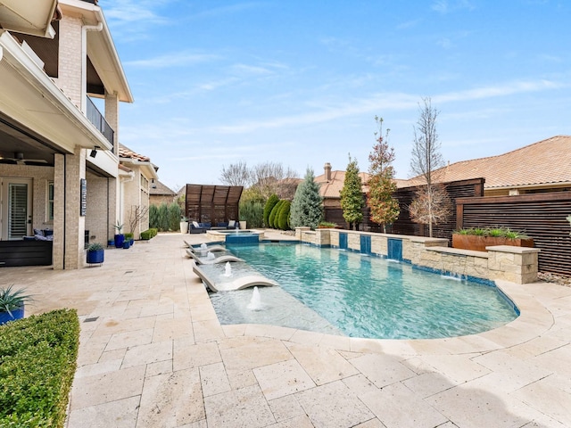 view of swimming pool featuring fence, a pool with connected hot tub, and a patio area