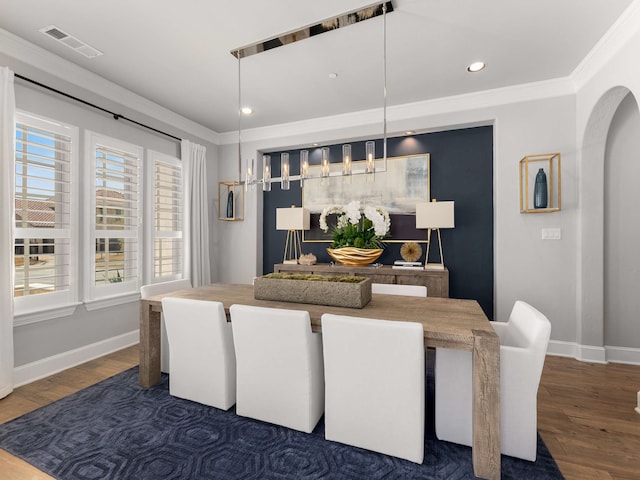 dining space with visible vents, dark wood-style floors, arched walkways, crown molding, and baseboards