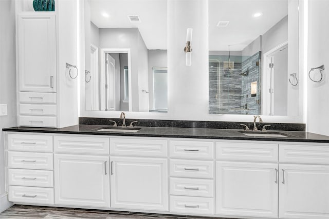 full bath featuring a stall shower, visible vents, a sink, and double vanity