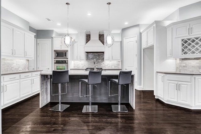 kitchen with dark wood-style floors, appliances with stainless steel finishes, visible vents, and custom range hood