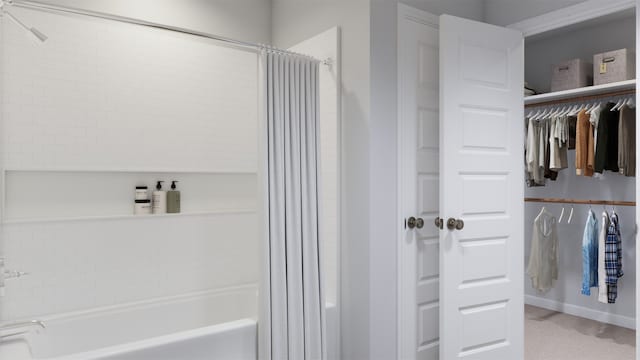 bathroom featuring shower / bath combo with shower curtain, baseboards, and a walk in closet