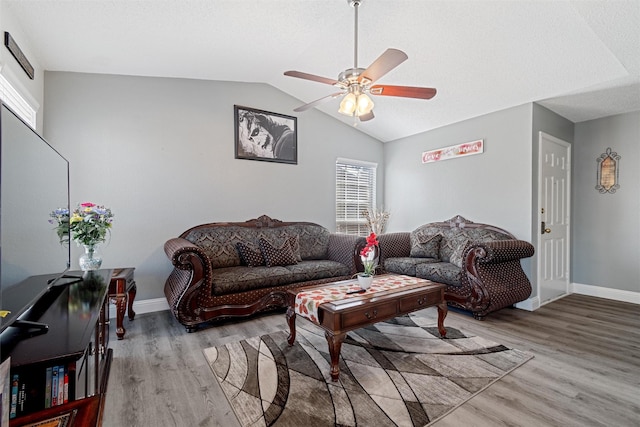 living area featuring lofted ceiling, ceiling fan, wood finished floors, and baseboards