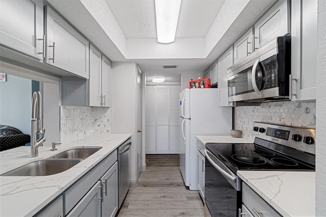 kitchen featuring light wood finished floors, visible vents, appliances with stainless steel finishes, gray cabinetry, and a sink