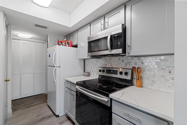 kitchen featuring a textured ceiling, appliances with stainless steel finishes, gray cabinets, and visible vents