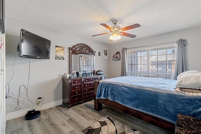 bedroom with light wood-style flooring, baseboards, ceiling fan, and a textured ceiling