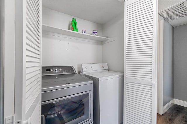 laundry area with laundry area, visible vents, baseboards, dark wood finished floors, and washing machine and dryer