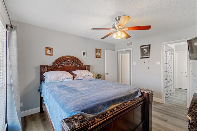 bedroom featuring a textured ceiling, light wood-style flooring, and baseboards