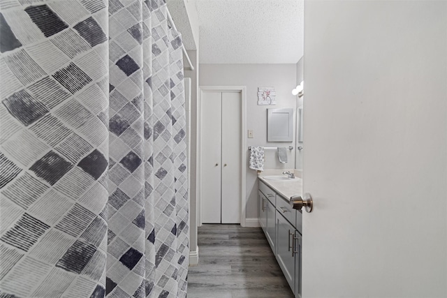 bathroom with baseboards, a shower, wood finished floors, a textured ceiling, and vanity