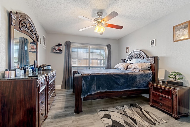 bedroom featuring light wood-style flooring, ceiling fan, and a textured ceiling