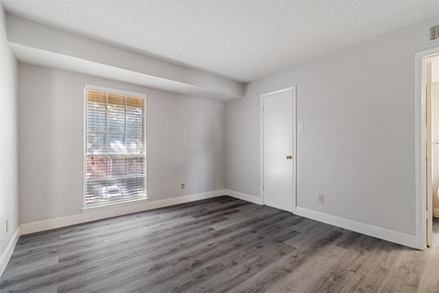 empty room featuring a textured ceiling, baseboards, and wood finished floors