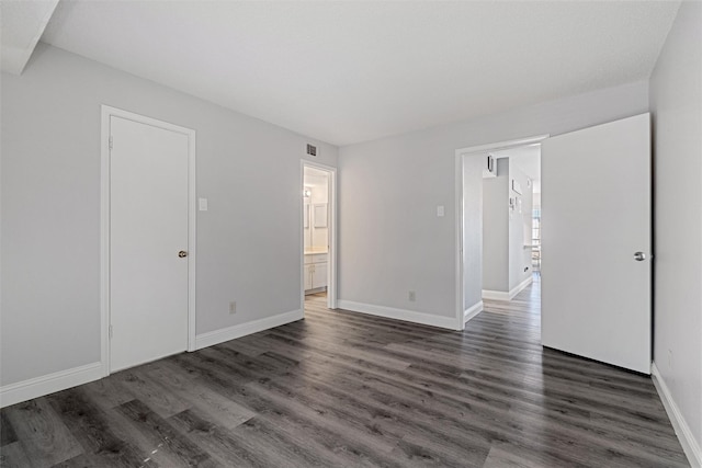 unfurnished bedroom featuring visible vents, dark wood finished floors, ensuite bath, and baseboards