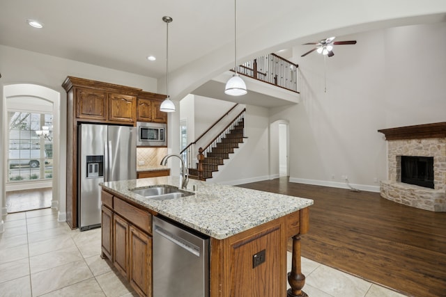 kitchen with arched walkways, a fireplace, a sink, open floor plan, and appliances with stainless steel finishes