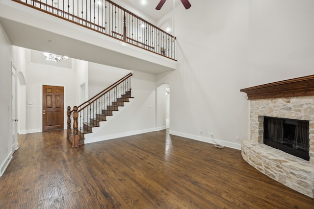 unfurnished living room with stairs, a fireplace, wood finished floors, and baseboards