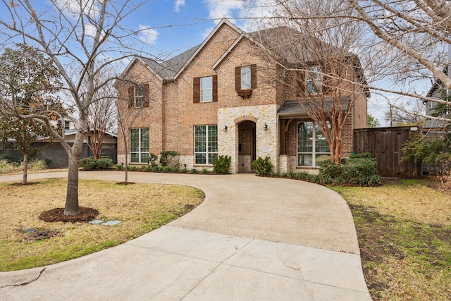 view of front of property with driveway, fence, and brick siding