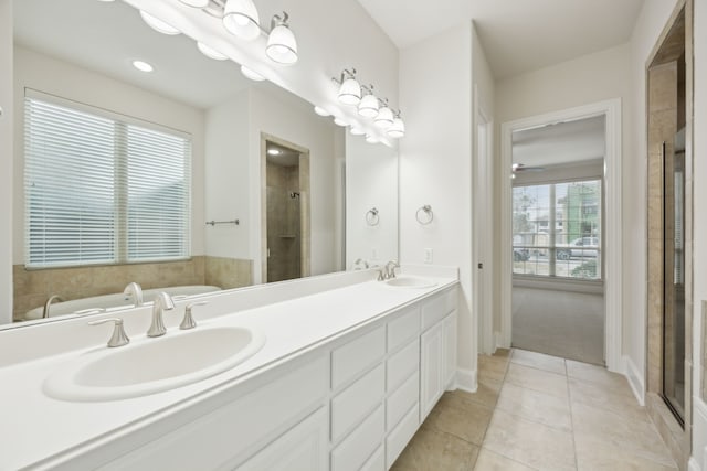 bathroom with a stall shower, double vanity, a sink, and tile patterned floors