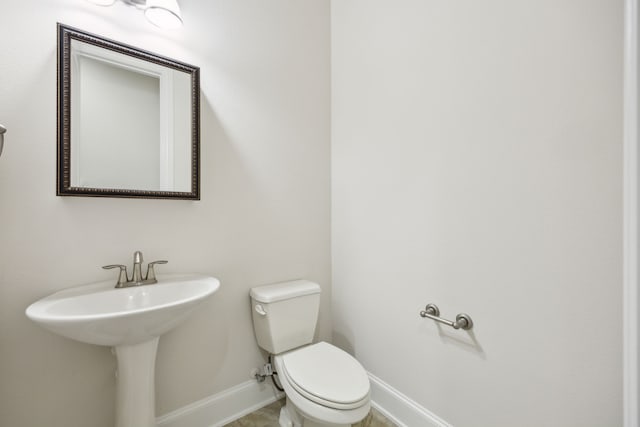 half bathroom with toilet and baseboards