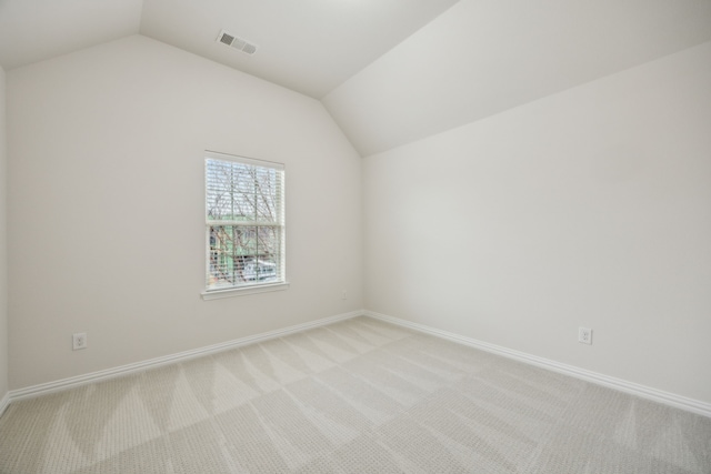 unfurnished room featuring light carpet, lofted ceiling, visible vents, and baseboards