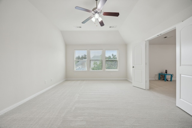 unfurnished room featuring light colored carpet, visible vents, vaulted ceiling, ceiling fan, and baseboards