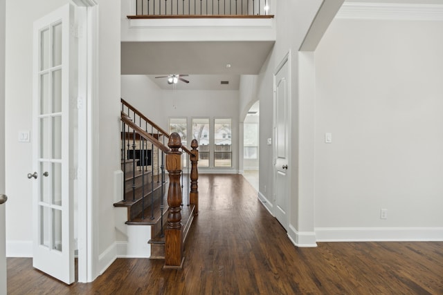 foyer entrance featuring baseboards, stairs, arched walkways, and dark wood finished floors