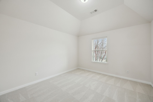 spare room with baseboards, visible vents, vaulted ceiling, and light colored carpet