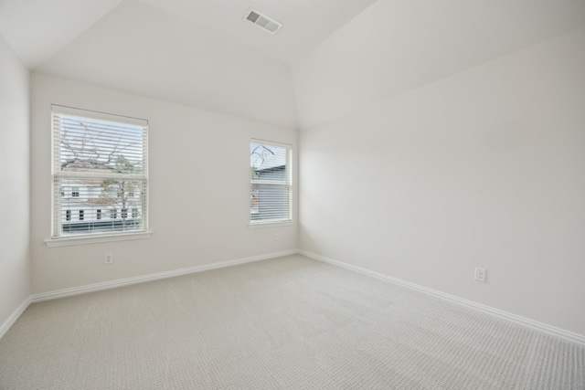 spare room featuring light carpet, baseboards, visible vents, and vaulted ceiling