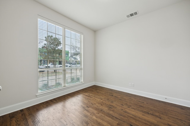 unfurnished room with baseboards, visible vents, and dark wood-type flooring