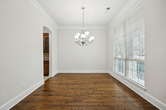 unfurnished dining area with baseboards, arched walkways, dark wood-style floors, crown molding, and a notable chandelier