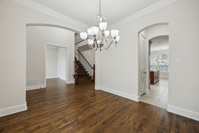 unfurnished dining area with visible vents, arched walkways, wood finished floors, an inviting chandelier, and crown molding