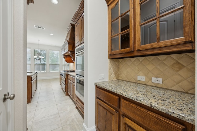 kitchen with visible vents, glass insert cabinets, light stone counters, backsplash, and light tile patterned flooring