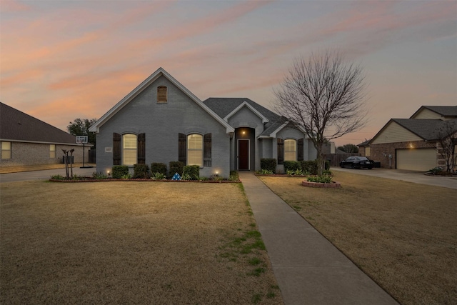 french provincial home featuring brick siding and a yard